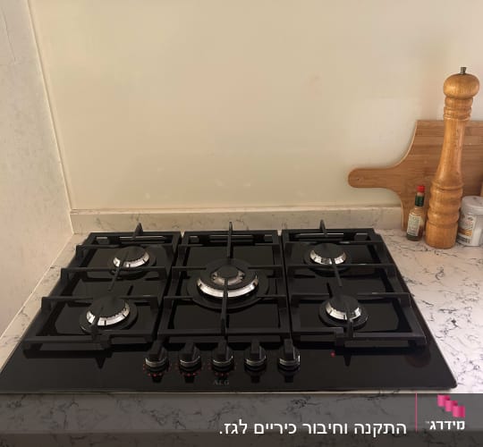 כיריים גז שחורות עם חמישה מבערים וכפתורי שליטה